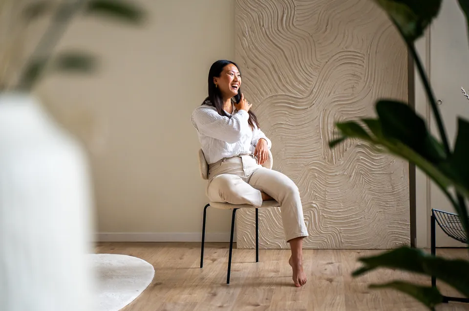 Brandingshoot in een lichte daglichtstudio: ondernemer zit lachend op een stoel