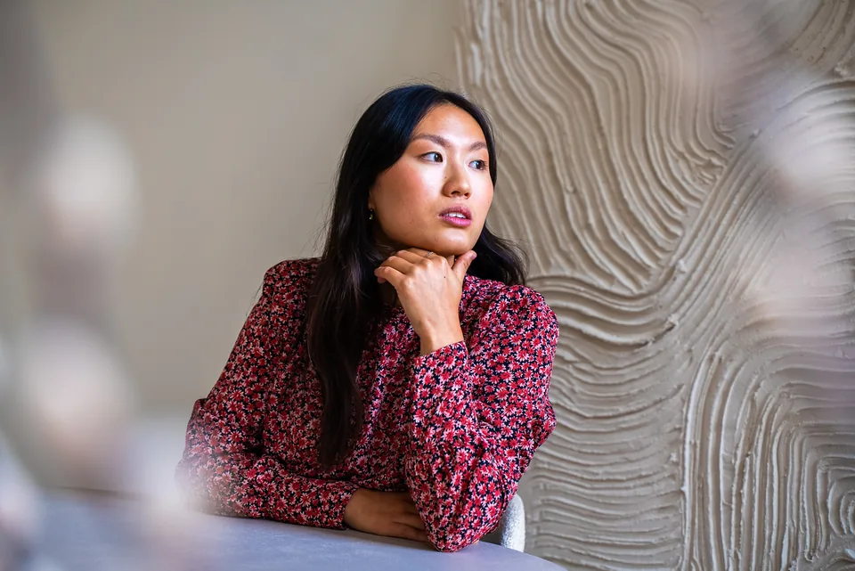 Ondernemer in een rode blouse tegen een lichte muur