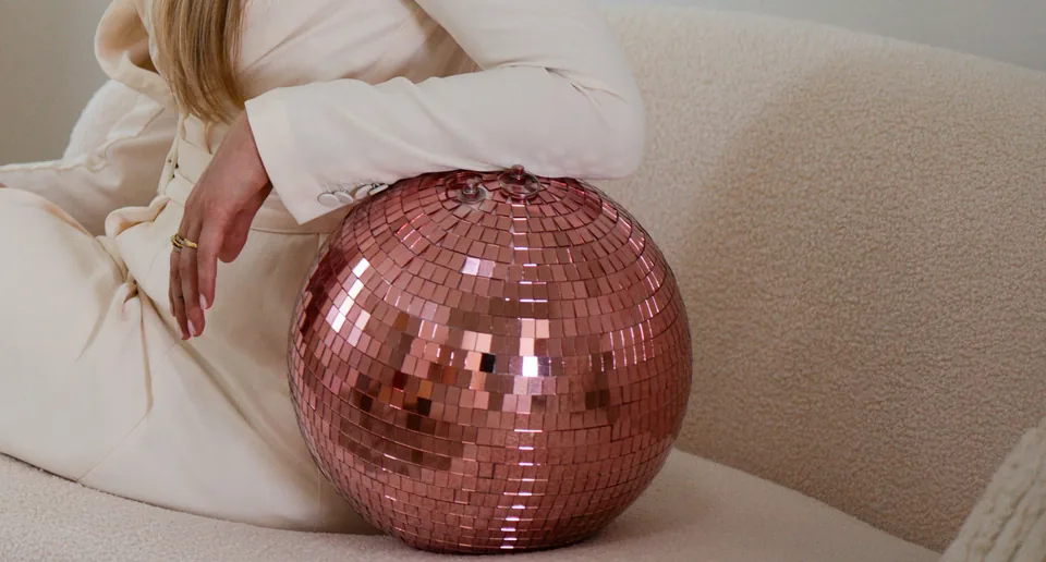 Detail van een roze discobal in een witte outfit