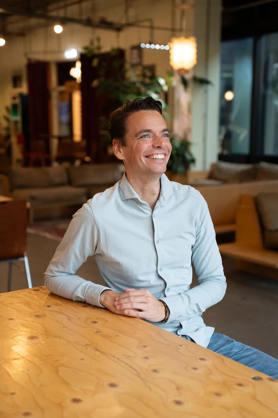 Lachende ondernemer aan een houten tafel kijkt opzij