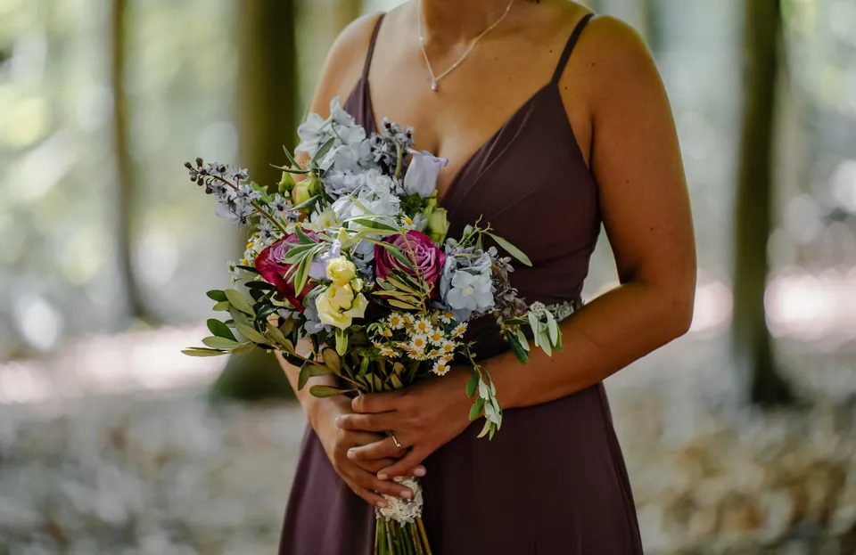 Bruidsboeket met wilde bloemen in de hand van de bruid