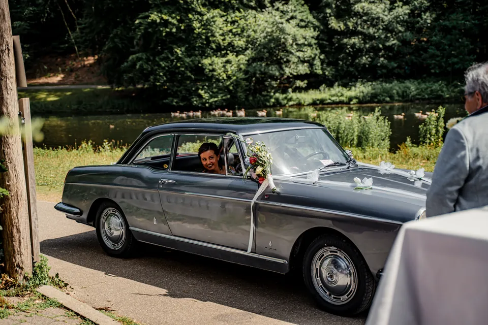 Klassieke trouwauto rijdt voor bij de trouwlocatie