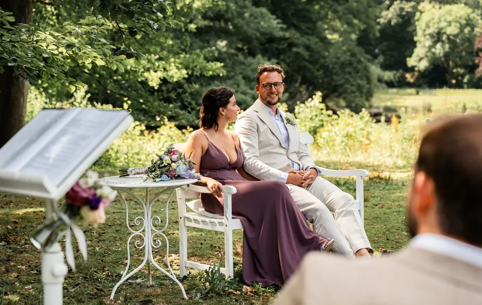 Bruidspaar zit tijdens de ceremonie in het park