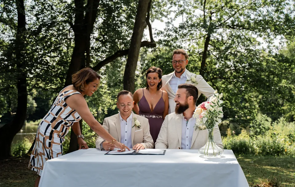 Het bruidspaar tekent buiten aan tafel