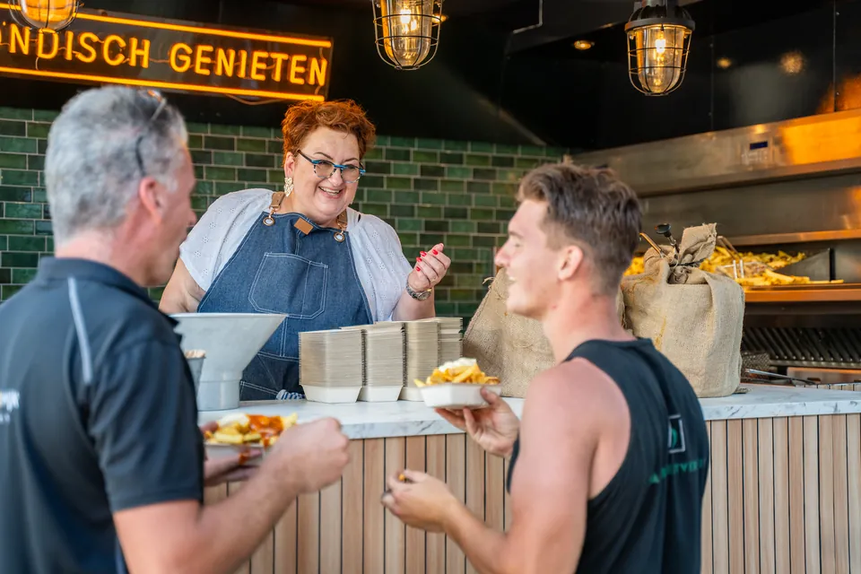 Gasten halen eten bij een foodstand tijdens een bedrijfsfeest