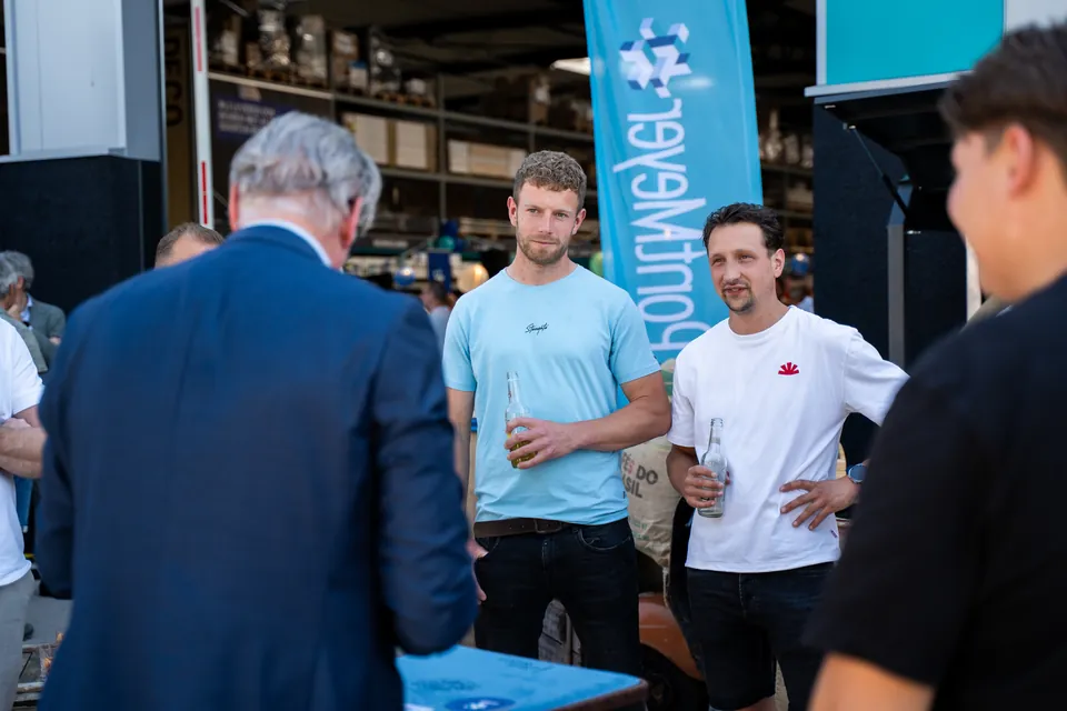 Collega's in gesprek tijdens een bedrijfsopening in een bouwmaterialenhal
