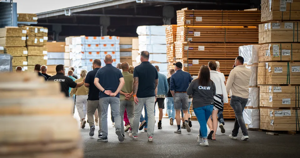 Gasten lopen door een houtopslag tijdens een bedrijfsevent