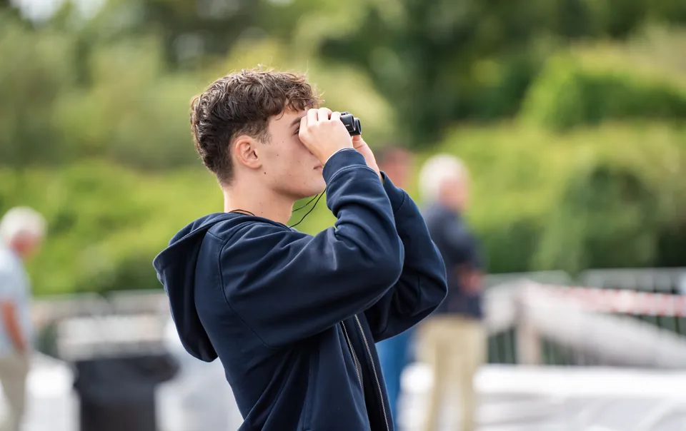 Jonge gast kijkt door een verrekijker tijdens Sail Amsterdam