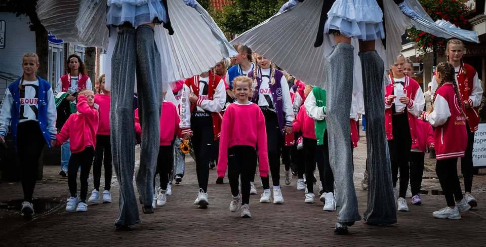 Dansgroep en steltlopers in een winkelstraat