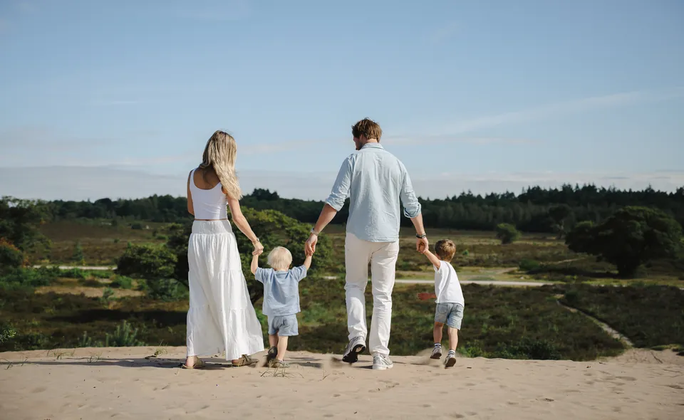 Gezin met twee jongens loopt hand in hand over de heide