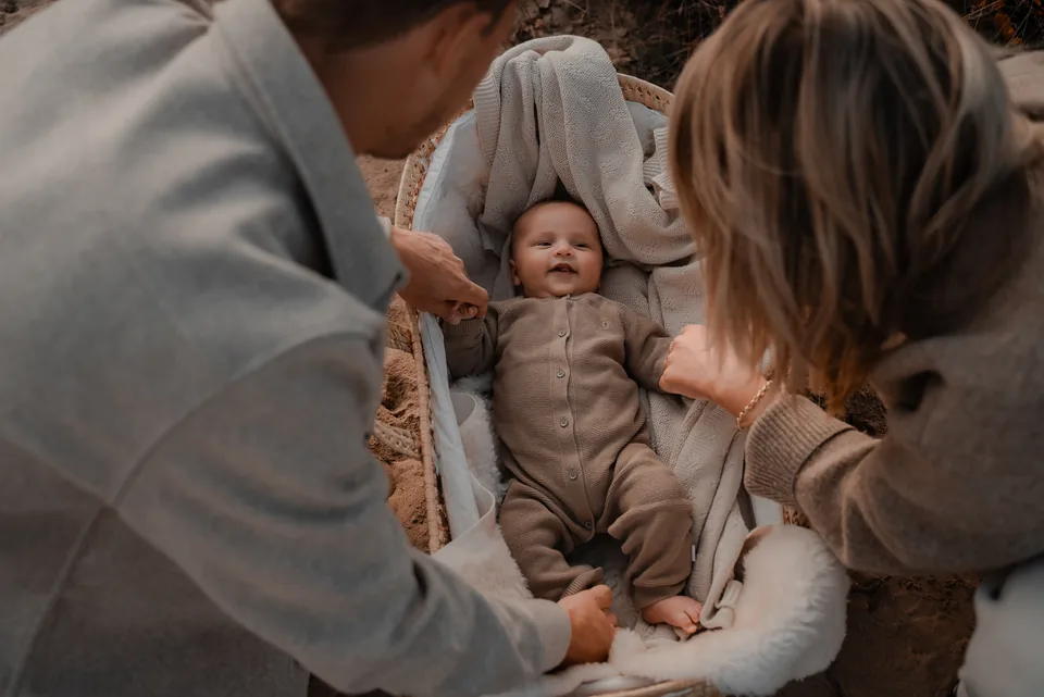 Ouders kijken naar hun baby in een rieten mandje op de heide