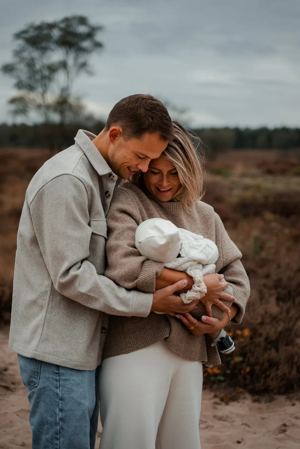 Ouders met hun baby dicht tegen elkaar op de heide