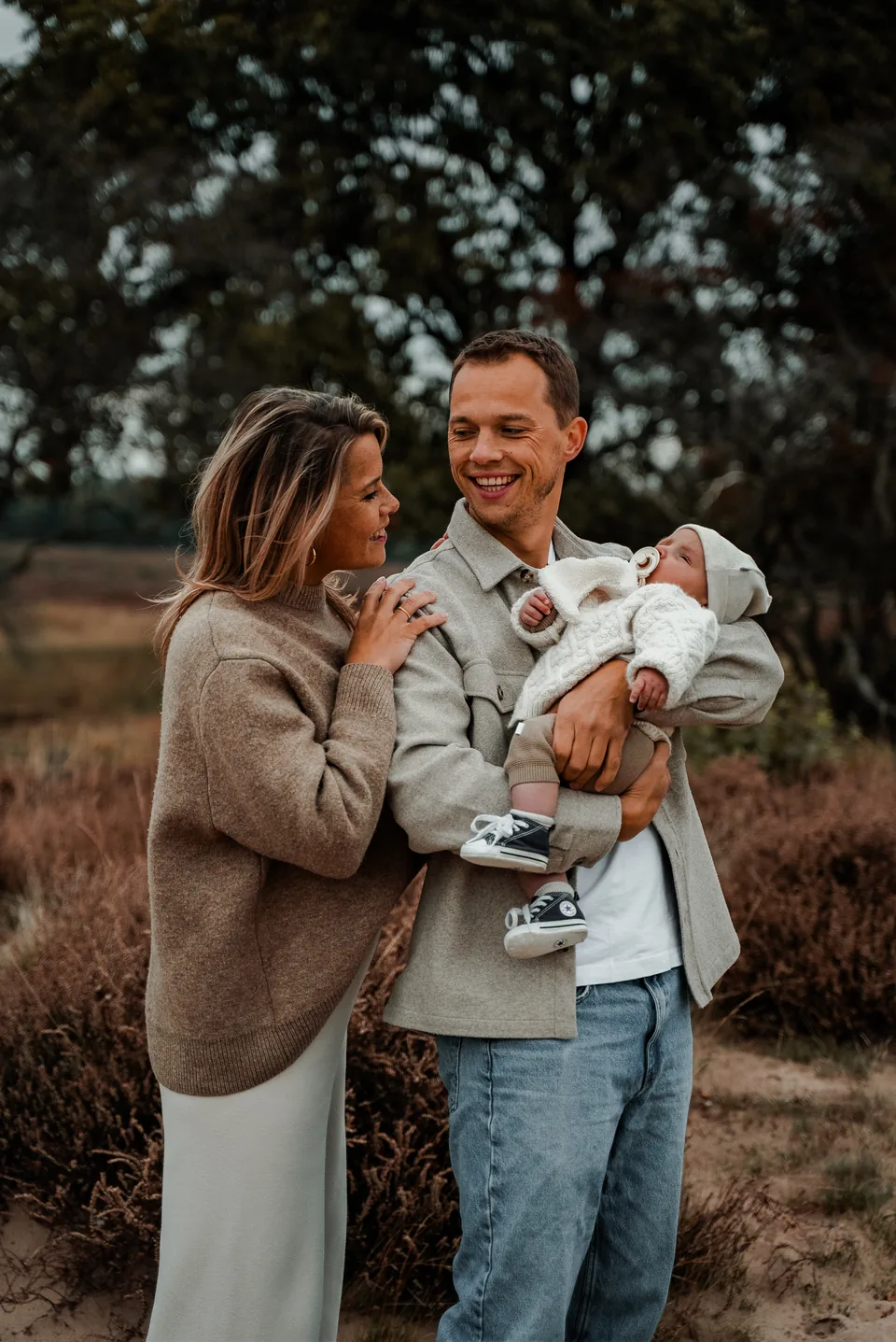Moeder houdt de baby vast terwijl vader lacht