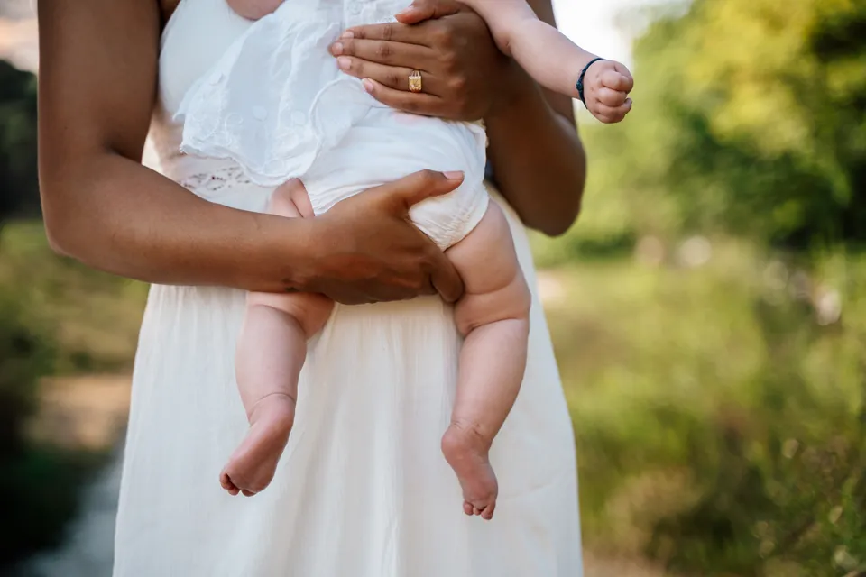 Baby op de arm van moeder in een witte jurk