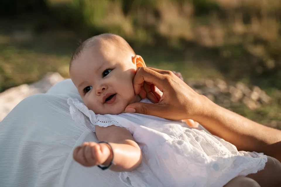 Baby ligt in de armen van moeder en kijkt in de camera