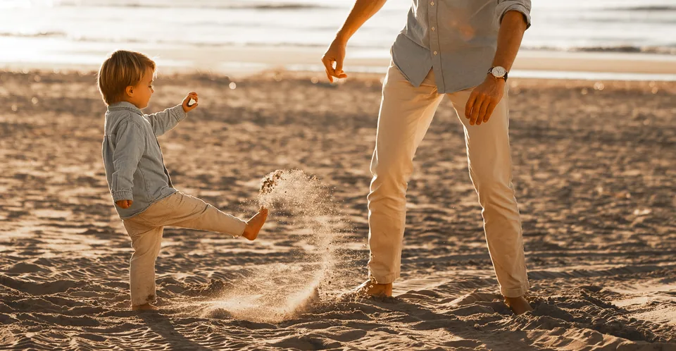 Jongetje schopt het zand op tijdens een familieshoot op het strand