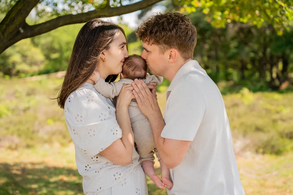 Ouders geven hun baby samen een kus