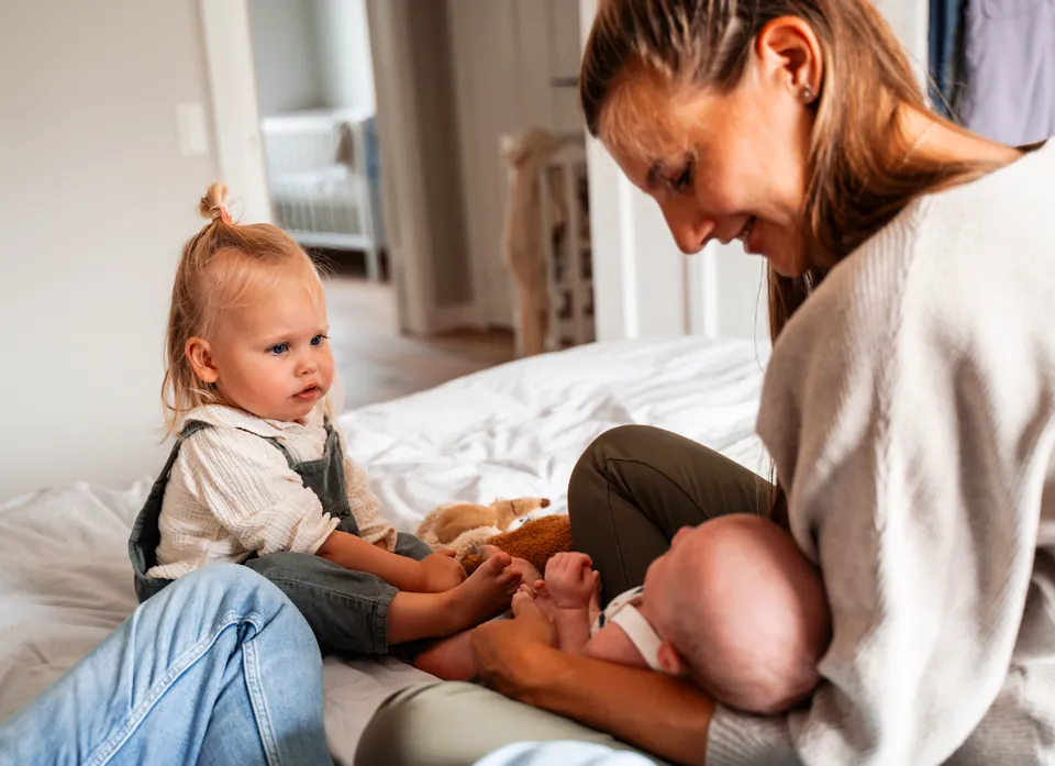 Moeder en peuter kijken naar de pasgeboren baby