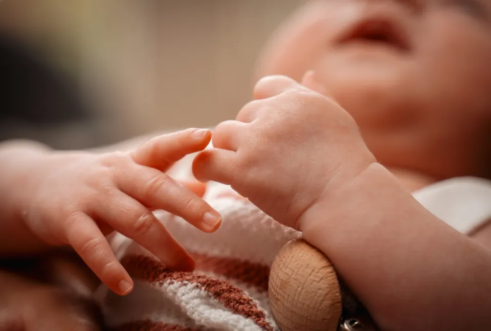 Klein babyhandje houdt een vinger vast