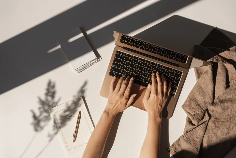 Handen typen op een laptop op een lichte werkplek