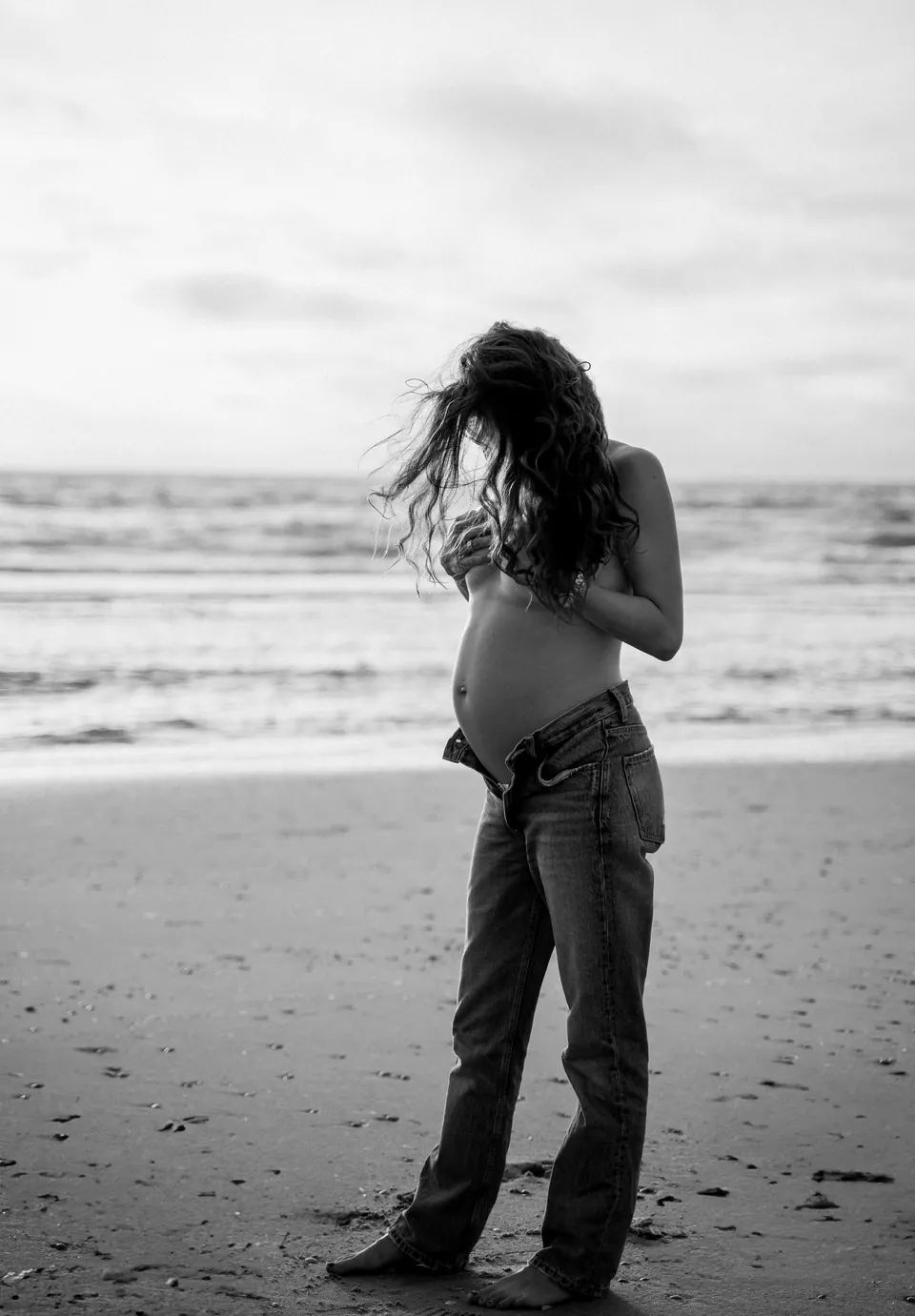 Zwart-witfoto van een zwangere vrouw aan zee