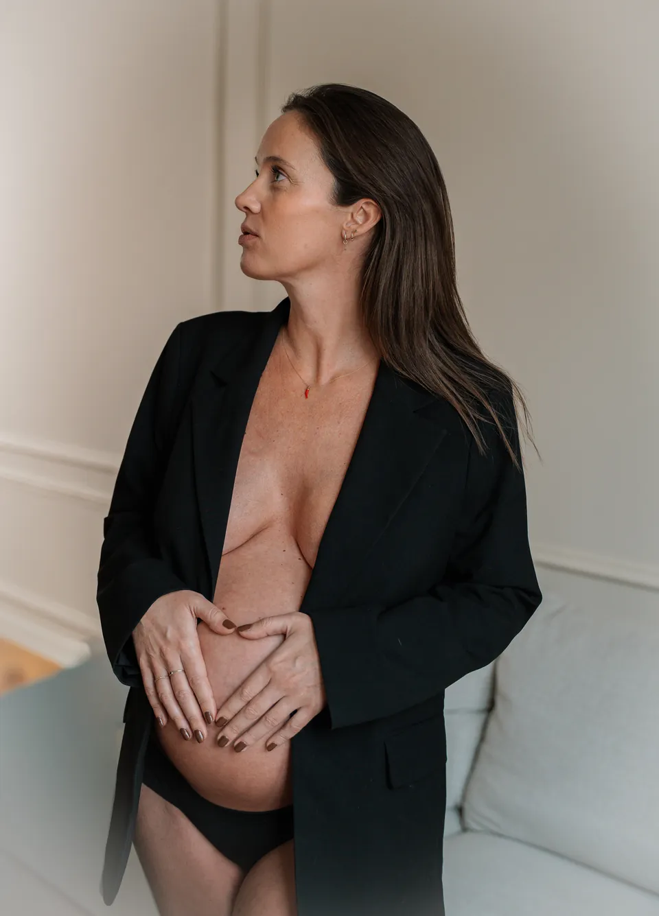 Zwangere vrouw in een zwarte blazer met haar handen op haar buik