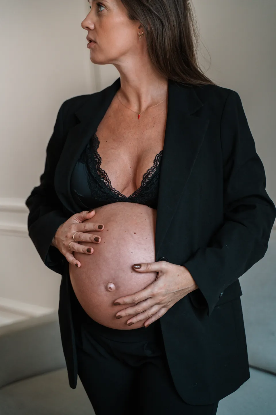 Zwangere vrouw in een zwarte blazer kijkt opzij